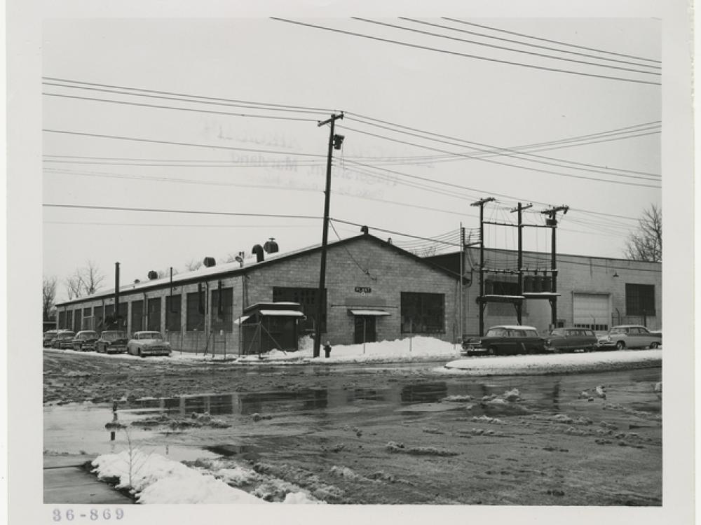 Exterior of a one-story industrial building with a wet, snowy parking lot in the foreground