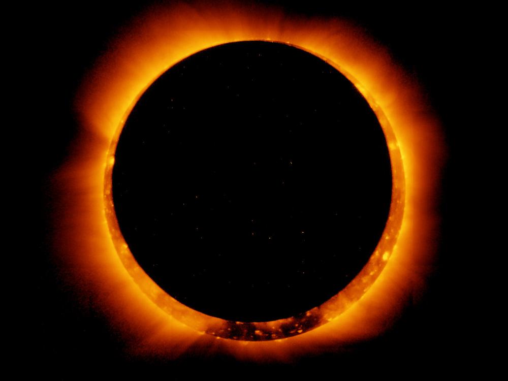 A photo of an eclipse of the sun, with looks like a black circle surrounded by a fiery halo.