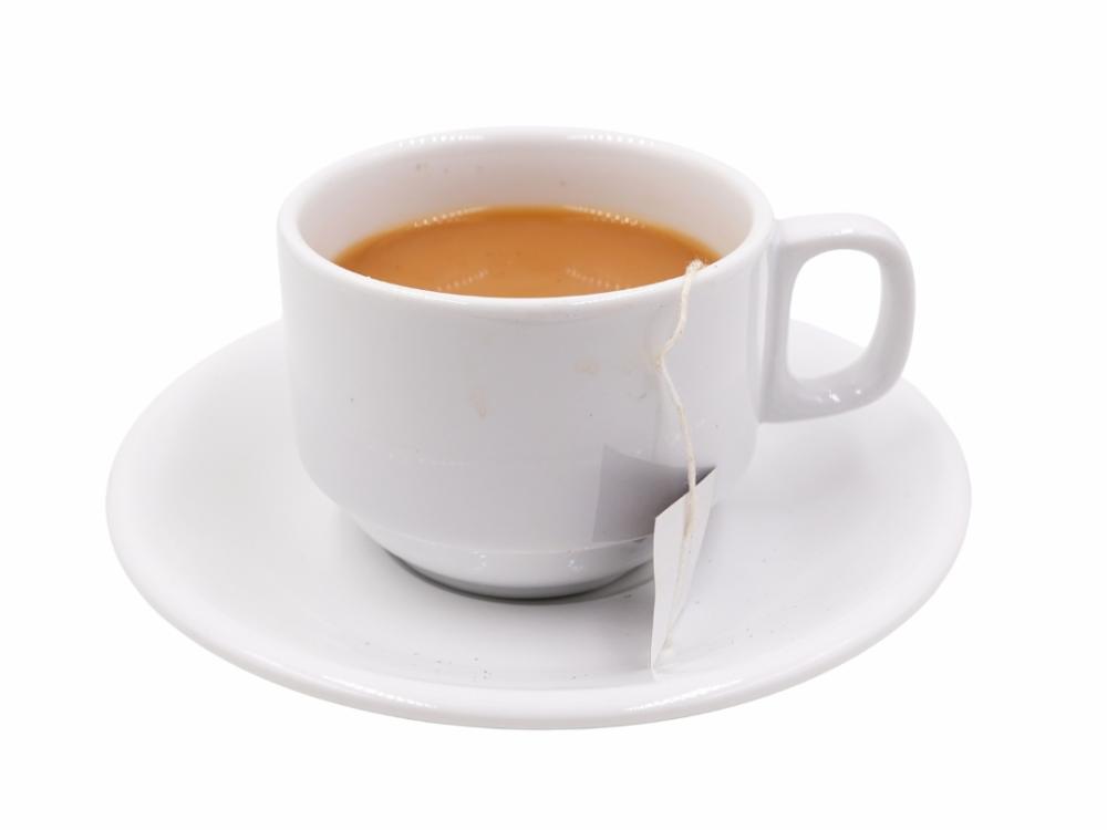 A white cup and saucer with tea in it. There's a tea bag in it. 