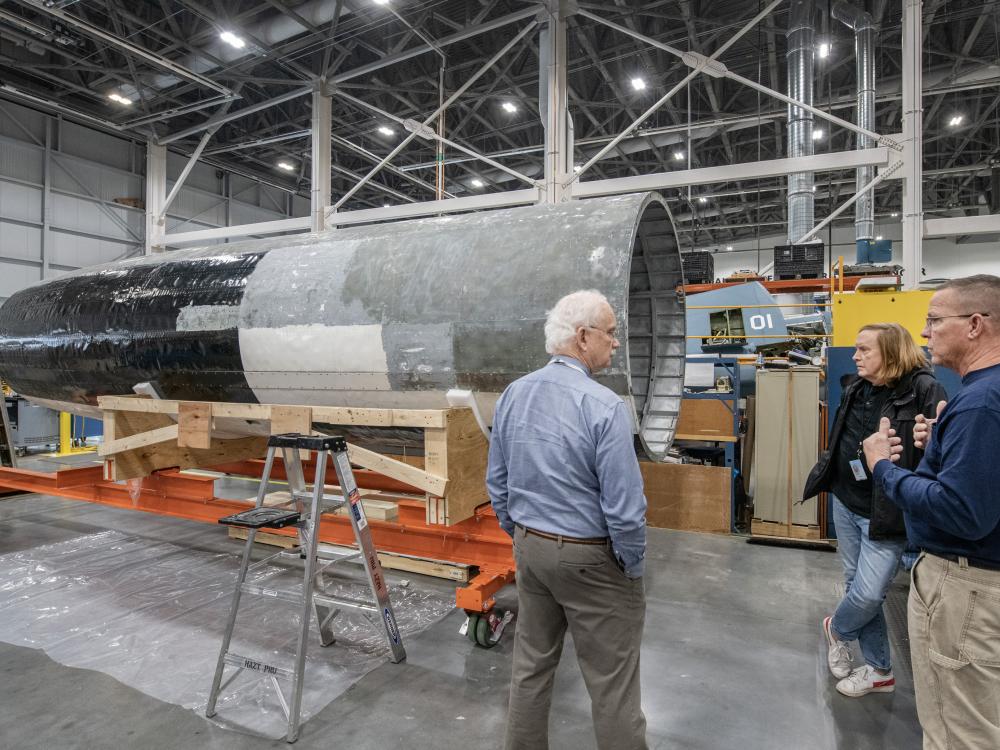 The individuals having a discussion in a restoration hangar.