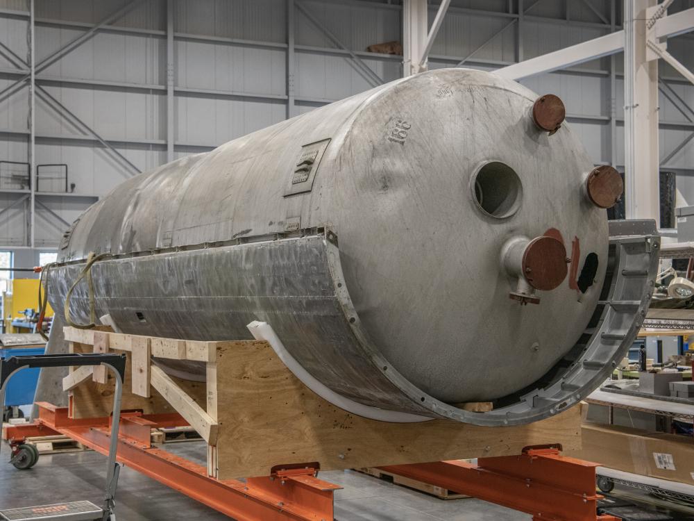 A large propellant tank sits on top of a wooden platform.