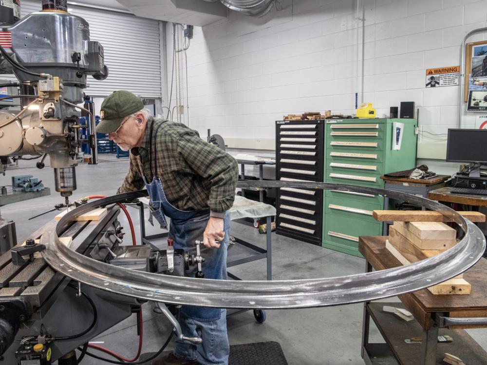 A man works on a large circular rocket part.