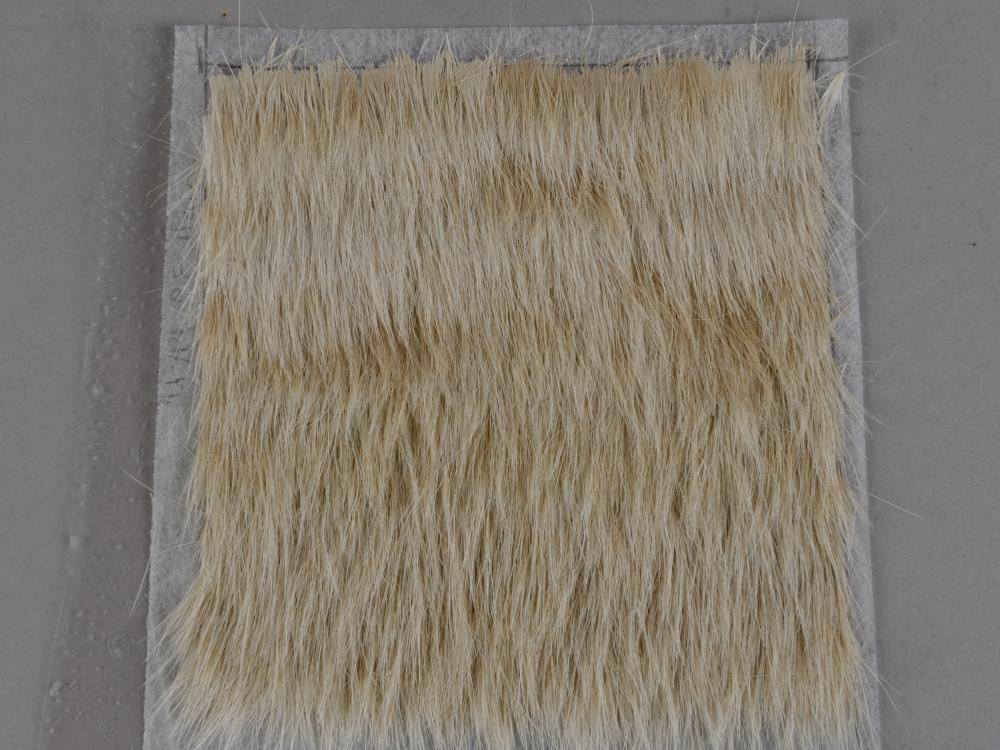 A sample of cow hair adhered to a spun-bond polyester substrate.