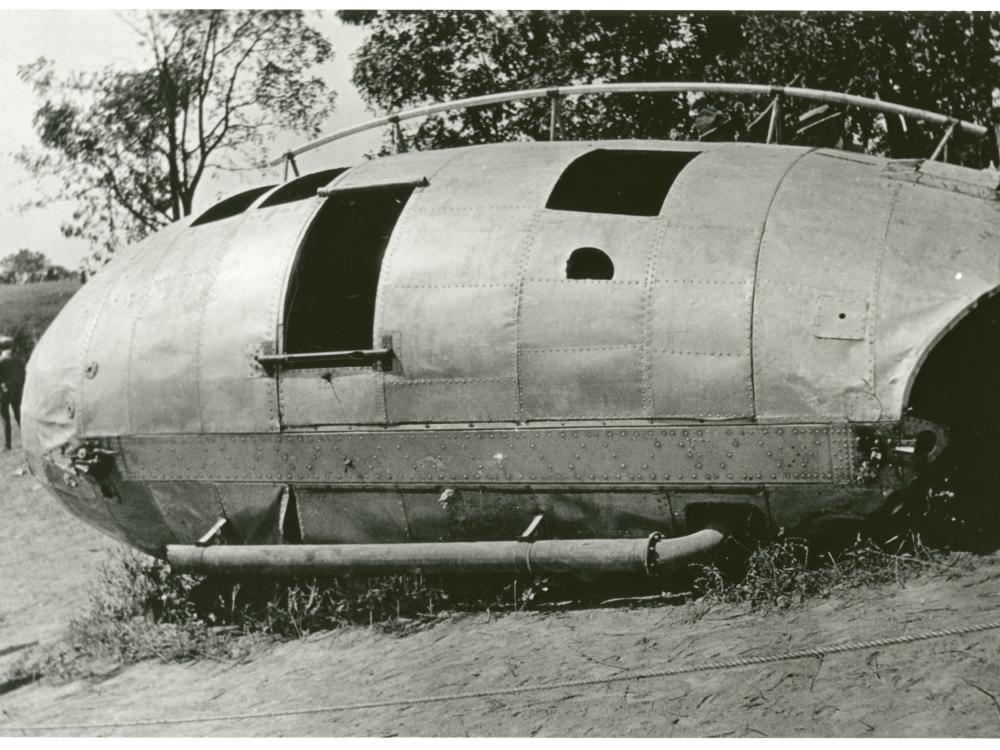 An oblong metal structure that has crashed into the tree line.