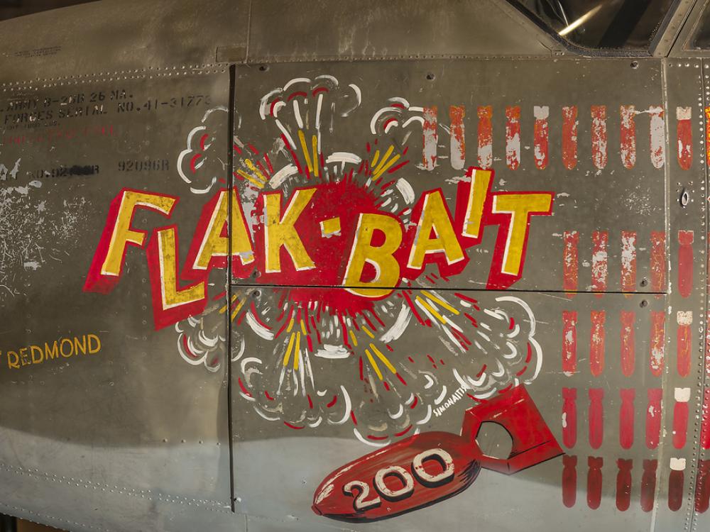 On the side of a bomber, the name "Flak-Bait" is painted, as well as an icon of a bomb with the number 200 on it and the name "O.J. Red Redmond."