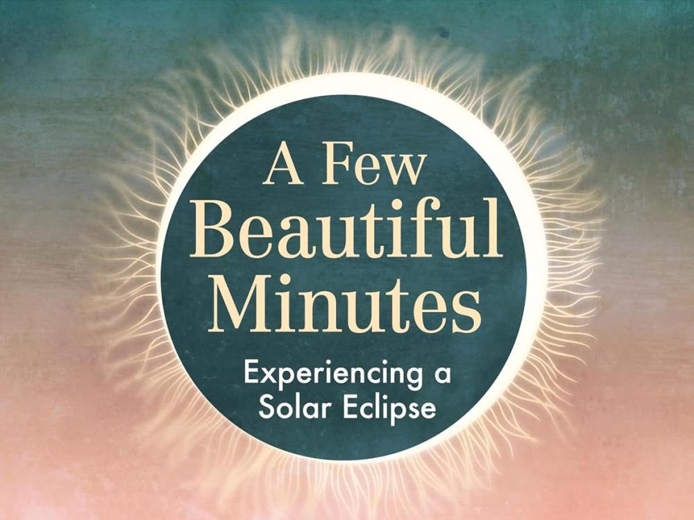 Children's book cover with a drawing of a solar eclipse (a black circle over a shining sun) over a pink and dark blue sky.  The title "A Few Beautiful Minutes: Experiencing a Solar Eclipse" is inside the black circle of the eclipse. There is a child wearing a red and white striped shirt and blue shorts underneath the solar eclipse with their arms outstretched. They are standing in a field of grass and flowers that are bending in the wind.