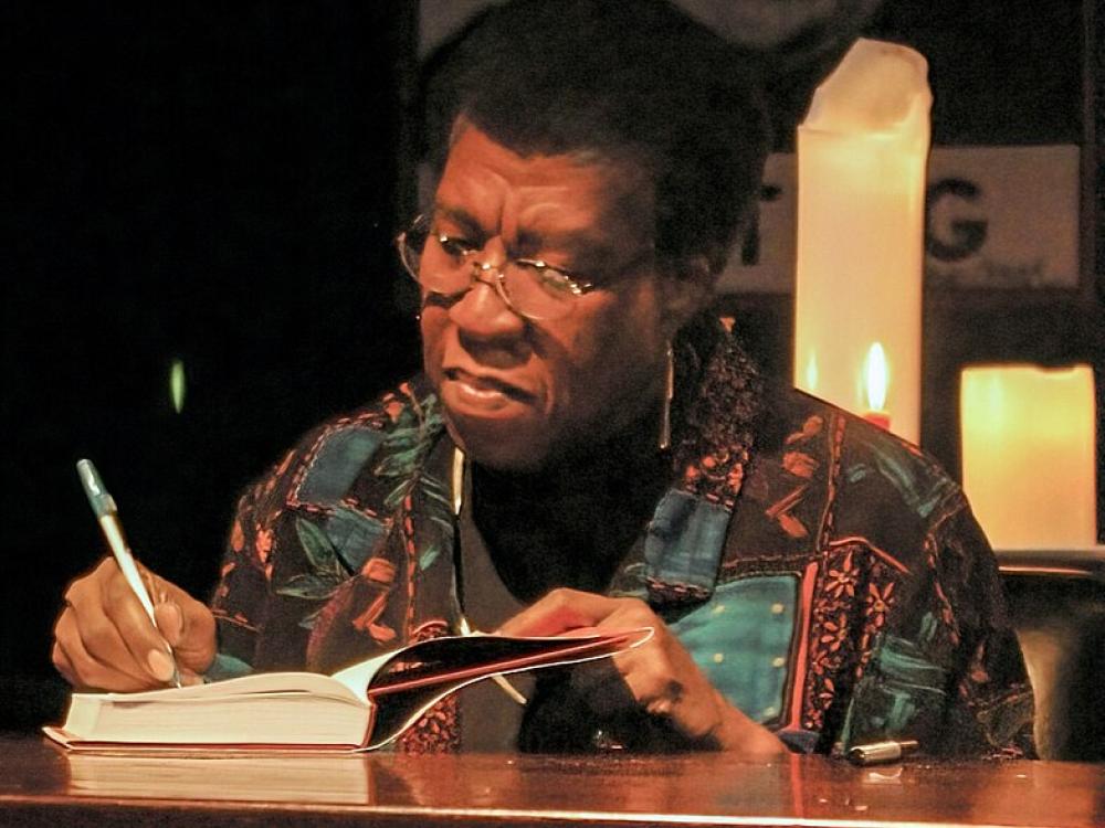 A senior African-American woman concentrates on signing a book. 