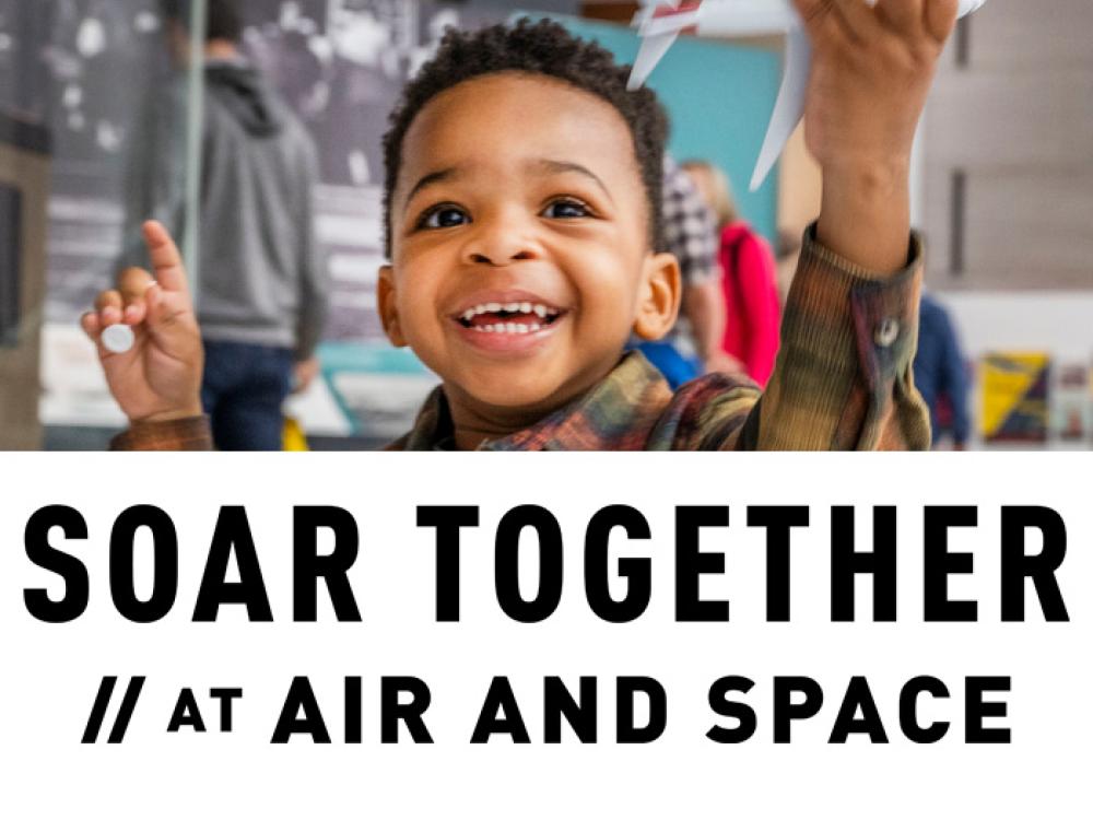 A young boy smiles, delighted by the model plane he holds in his hand. Overtop the image is the text "Soar Together at Air and Space."
