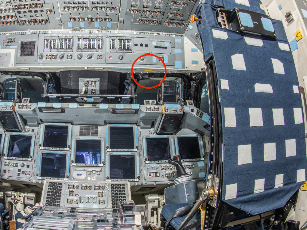 The interior cockpit of a space shuttle, featuring an array of control panels with numerous switches, buttons, and screens, highlighting the intricate operations required to pilot such a craft.