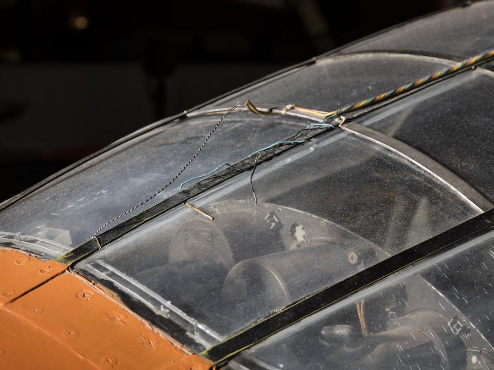 Top view of cockpit of an airplane. The airplane is painted orange and the cockpit window is closed. 