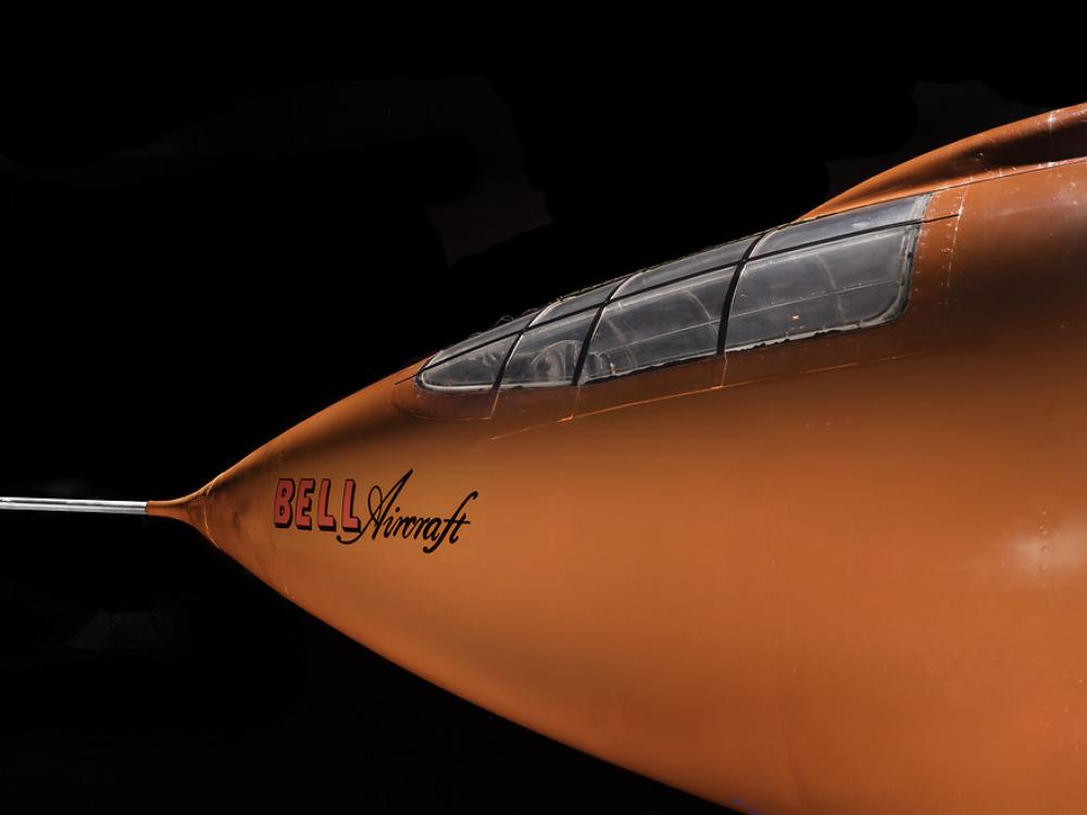 Side view of nose of an aircraft. The aircraft is painted orange. 