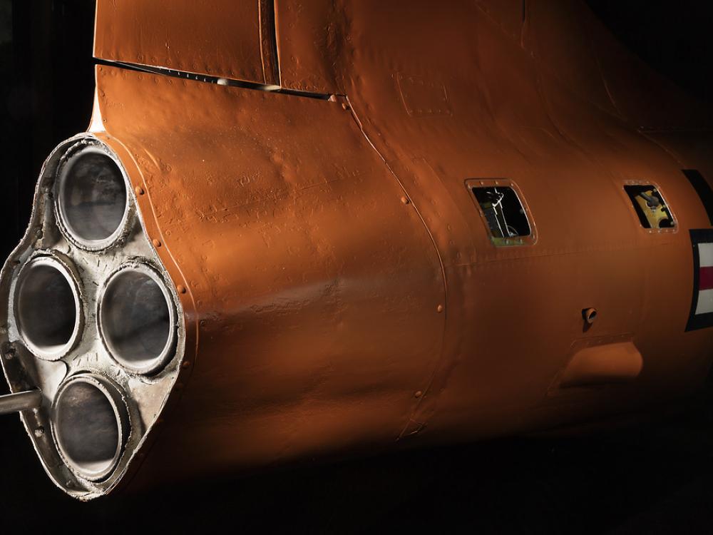 Side view of engine of an aircraft with three exhaust valves. The aircraft is painted orange. 