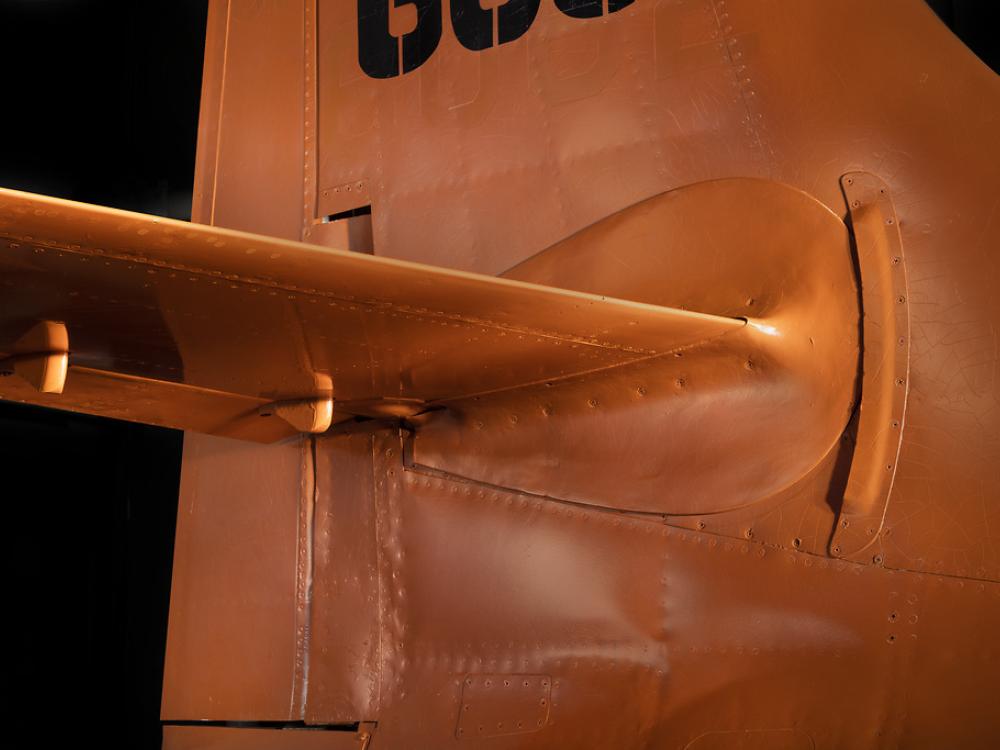 Close up of vertical and horizontal stabilizer of an aircraft. The aircraft is painted orange. 