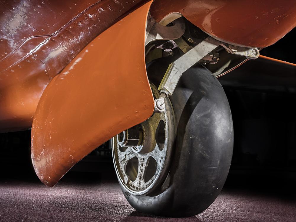 View of a tire on an aircraft. The aircraft is painted orange. 