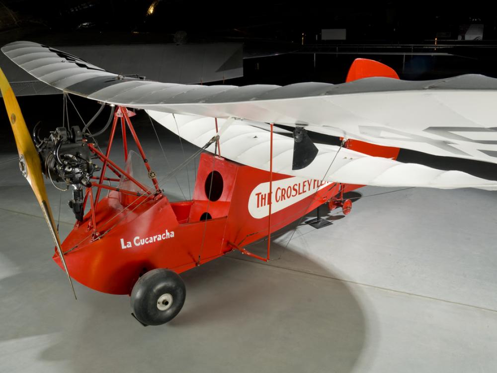 Wing of a red and white open-cockpit staggered wing aircraft 