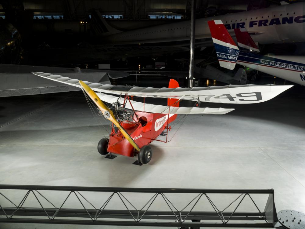 Red and white open-cockpit staggered wing aircraft on display at the museum. 