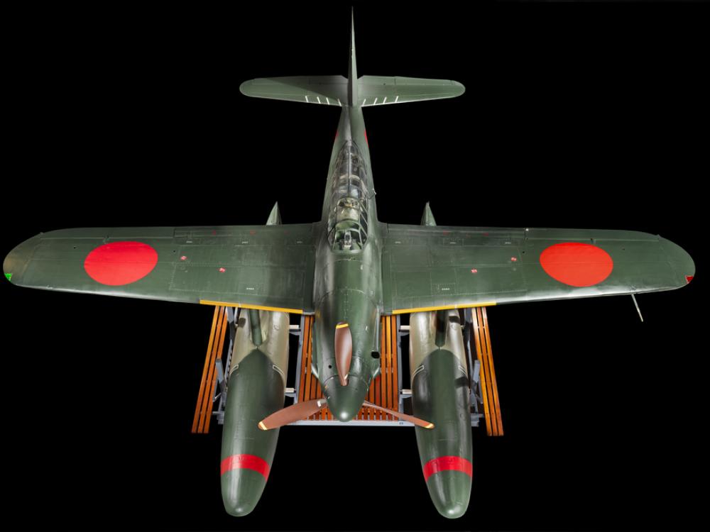 Above view of a green bomber with red roundels on the wings and twin floats in place of wheels.