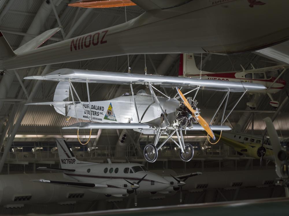 Silver painted biplane with wood propellers. Huff-Daland Duster is painted on the side of the plane.