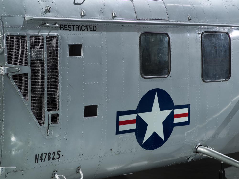 United States Coast Guard insignia painted on the fuselage of a silver helicopter.