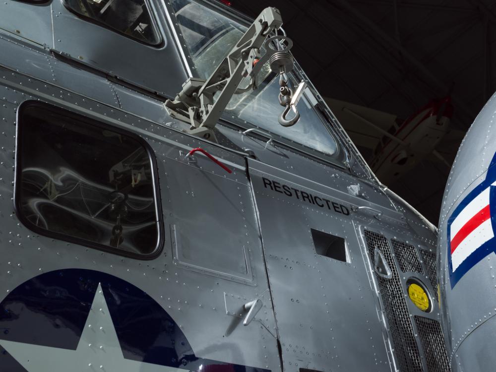 View of a cargo hook, windows, and the word restricted painted on the helicopter. 