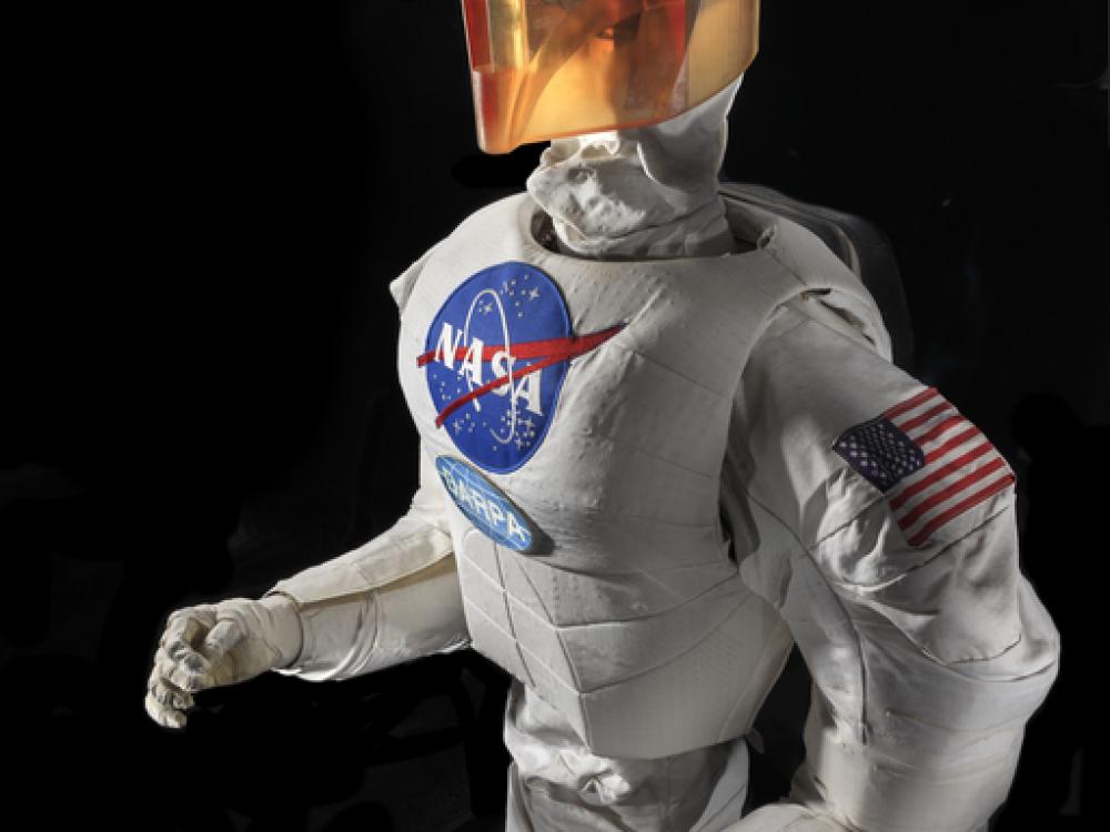 Upper body of a robot with arms, chest with a NASA logo, and an orange face cover.