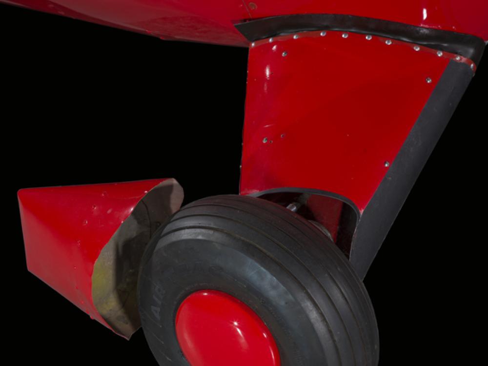 Close up of a tire and landing gear of a red painted plane.