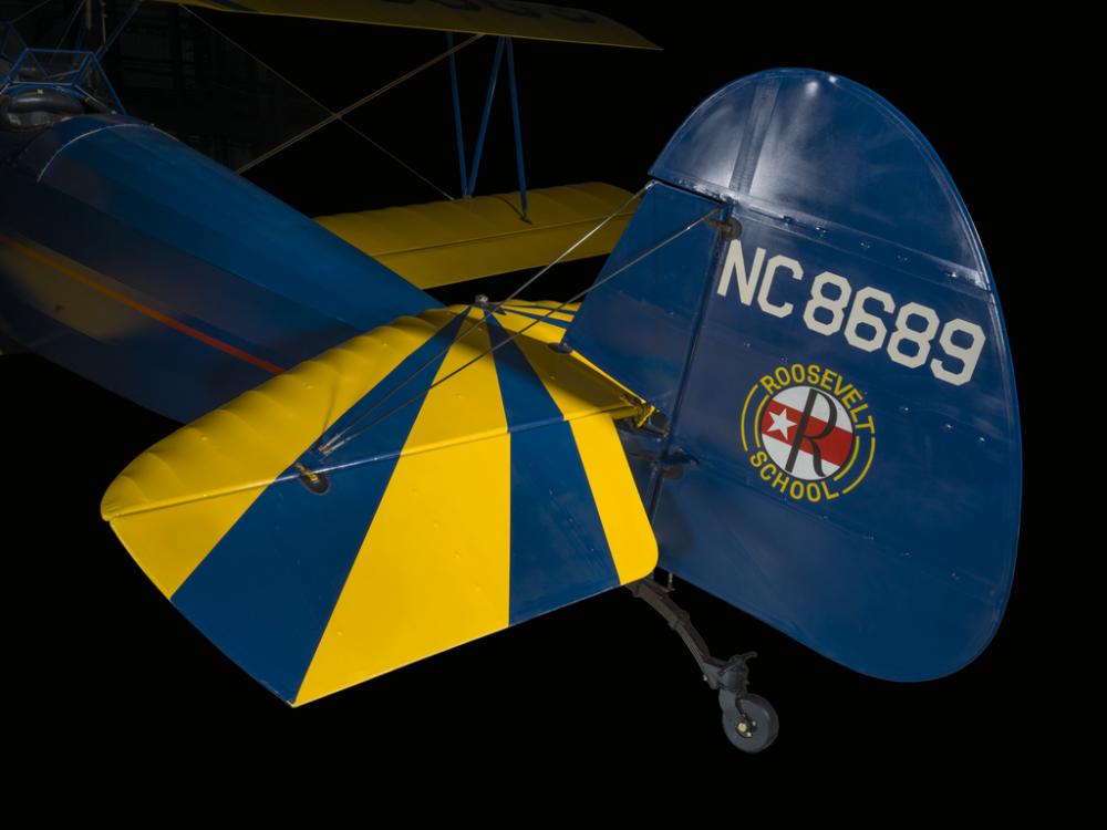 Rudder attached to a yellow and blue painted aircraft. NC8689 is painted on the rudder. 