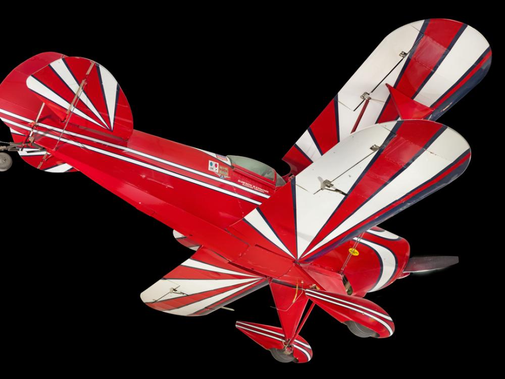 View of the undercarriage of a red, white, and blue painted aerobatic biplane. 