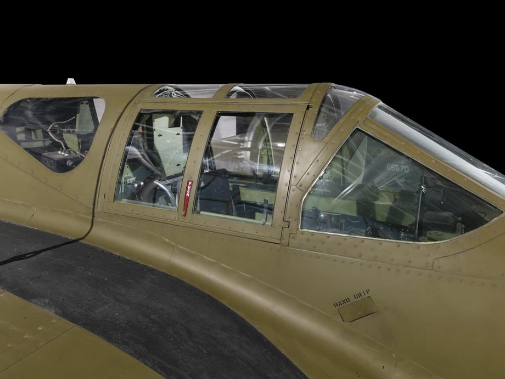 Close up view of a cockpit of a green painted jet aircraft. 