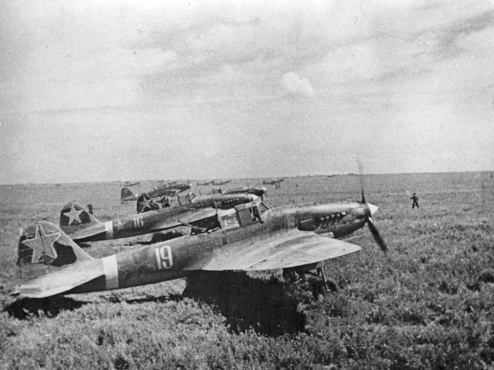 Historical photo of several aircraft on a grassy field. 