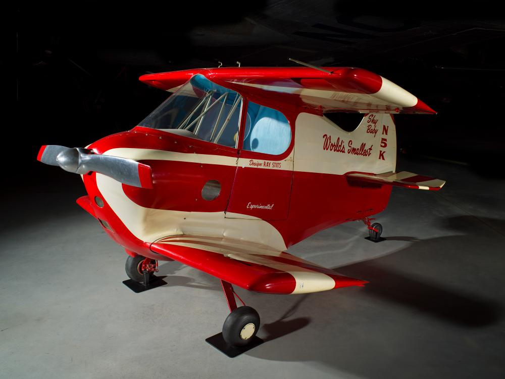 A tiny red and white aircraft. It gives the effect of a toy car, made lifesize.