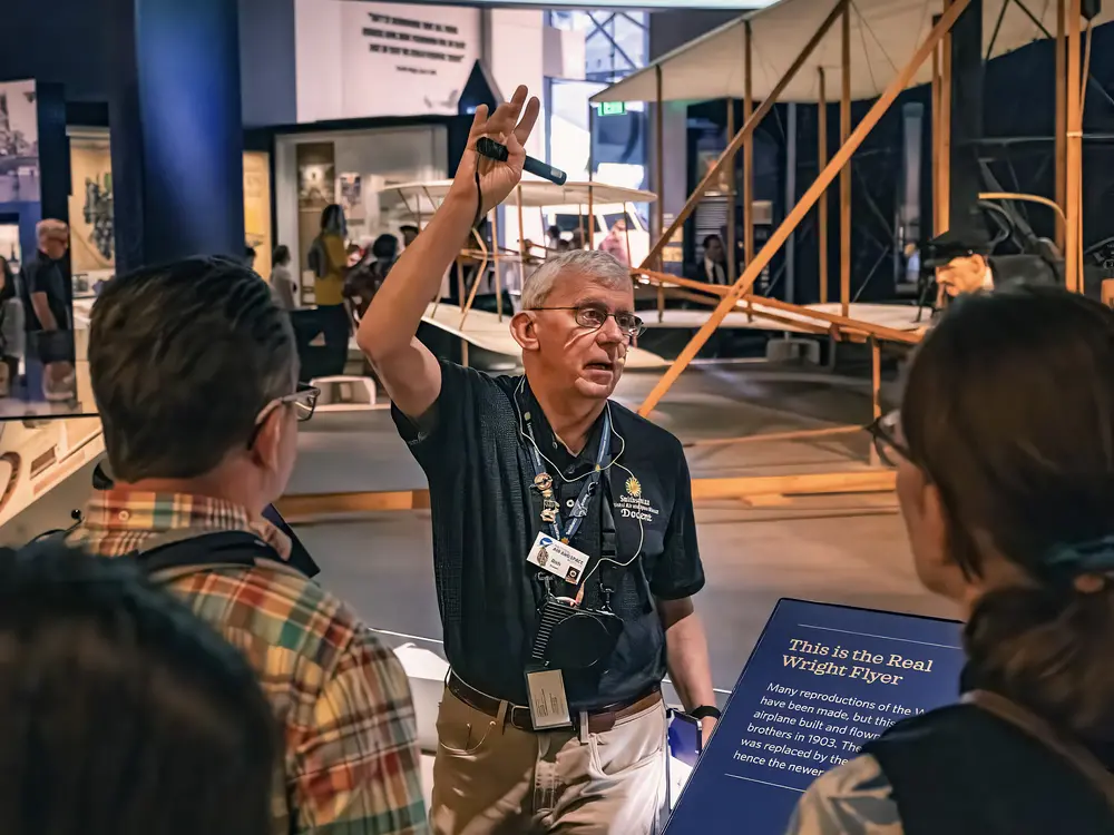 A docent raises his arm in the air while explaining the Wright Brothers.
