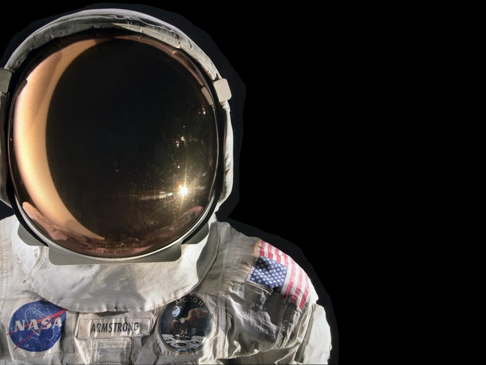 On the left side of the image, a crisp white spacesuit and helmet contrasts with the black background. 