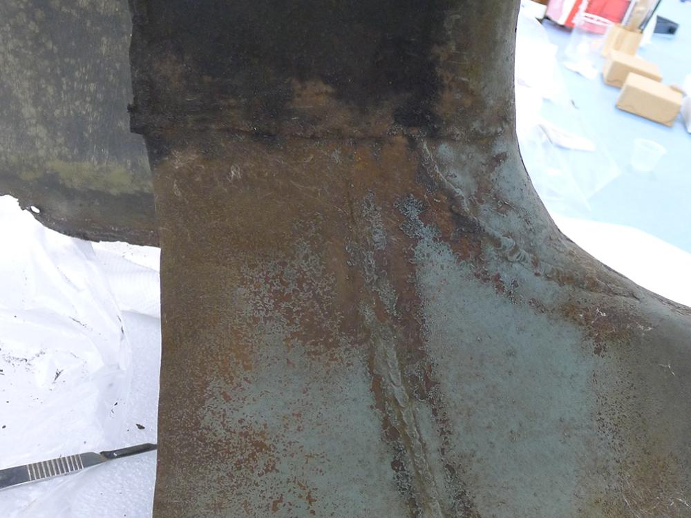 A section of the Horten Ho 229 V3, a gray metal aircraft. This section is showing signs of age through discoloration. The top section has not been cleaned, whereas the bottom section has been cleaned.