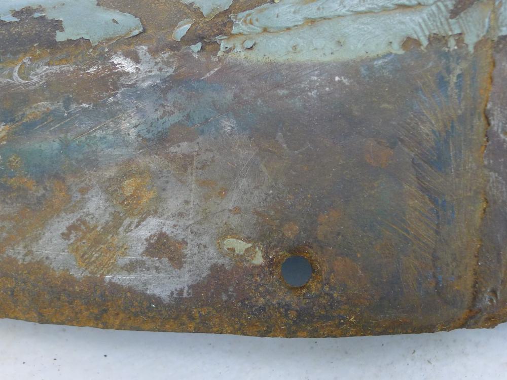 A cover section of a World War II aircraft shows a black surface underneath paint, dirt, grime, and preservatives.