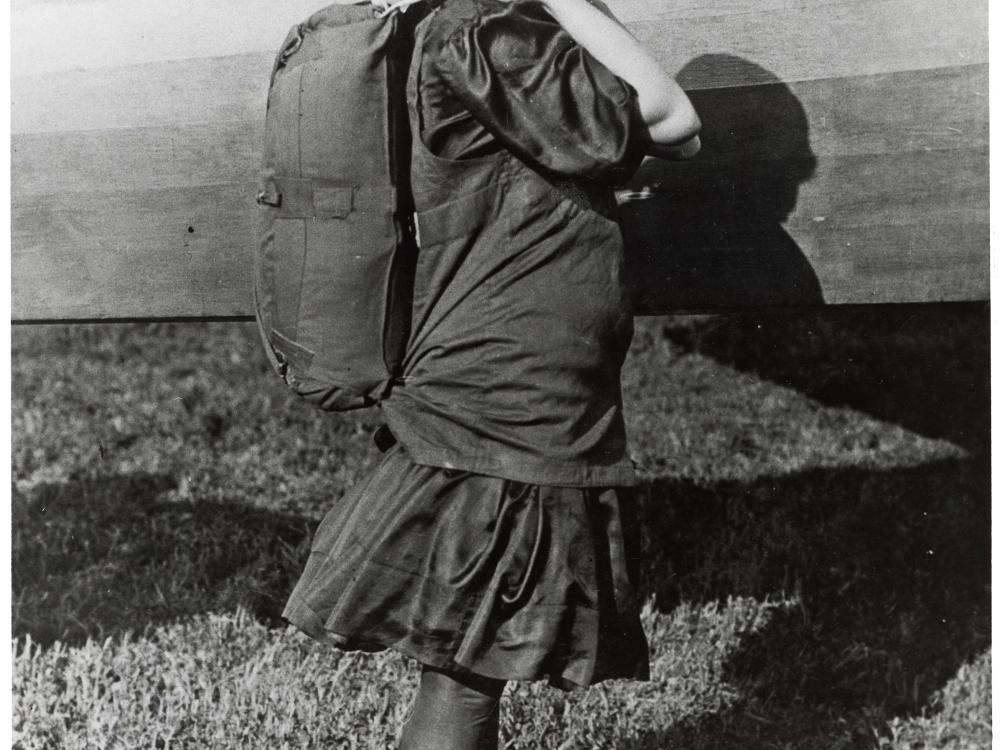 Tiny Broadwick, a white female parachutist, wears a back-pack parachute.