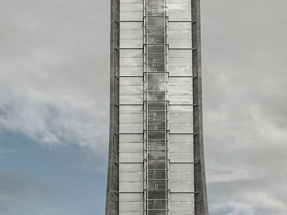 Partial view of the air traffic control at Oslo Airport in Norway. This portion of the tower has dark gray-colored steel sides which open up to possess lighter gray brick-like patterns in between another section of darker gray steel.