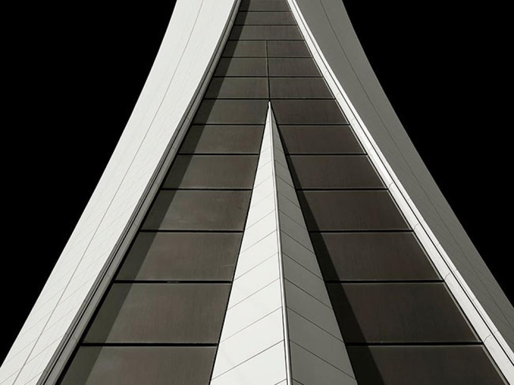 Partial view of the base of an air traffic control tower in Dubai. The base features a gray concrete stacking pattern with white ornate edges and details.