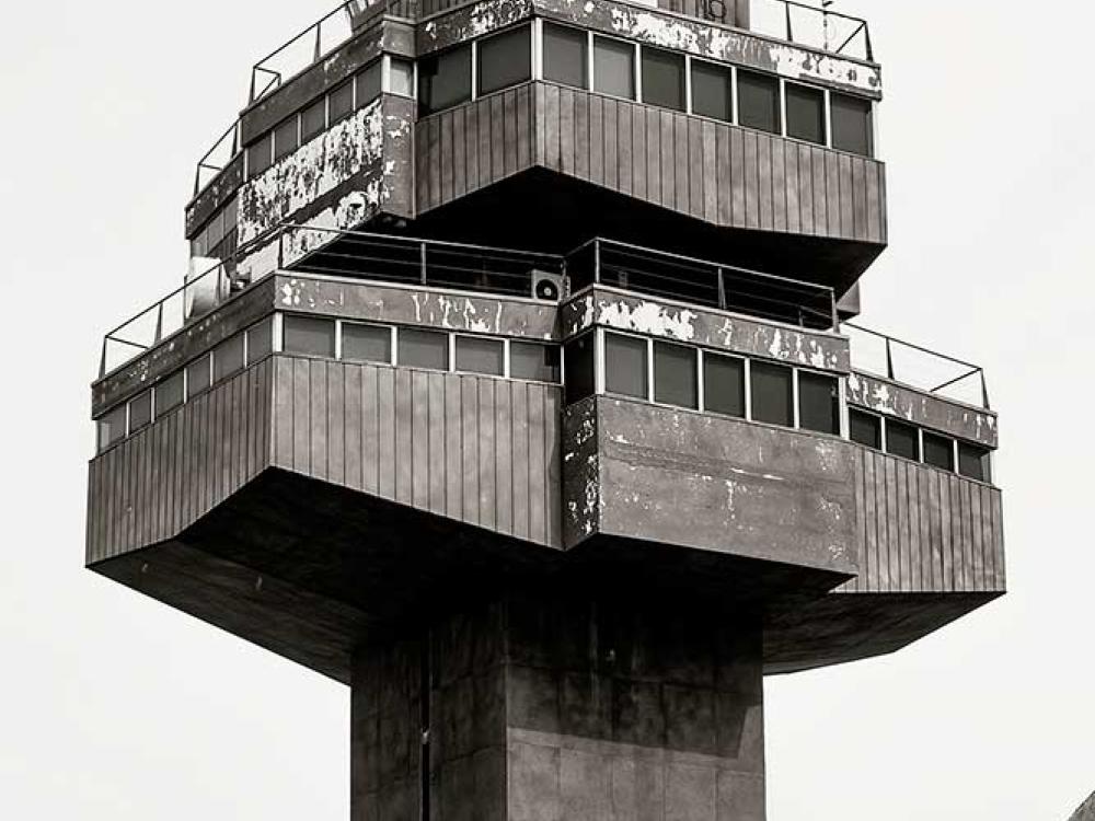 Partial view of the air traffic control tower at Barcelona El-Prat Airport. The tower features a steel base with three floors of operations, each floor smaller than the one before it.