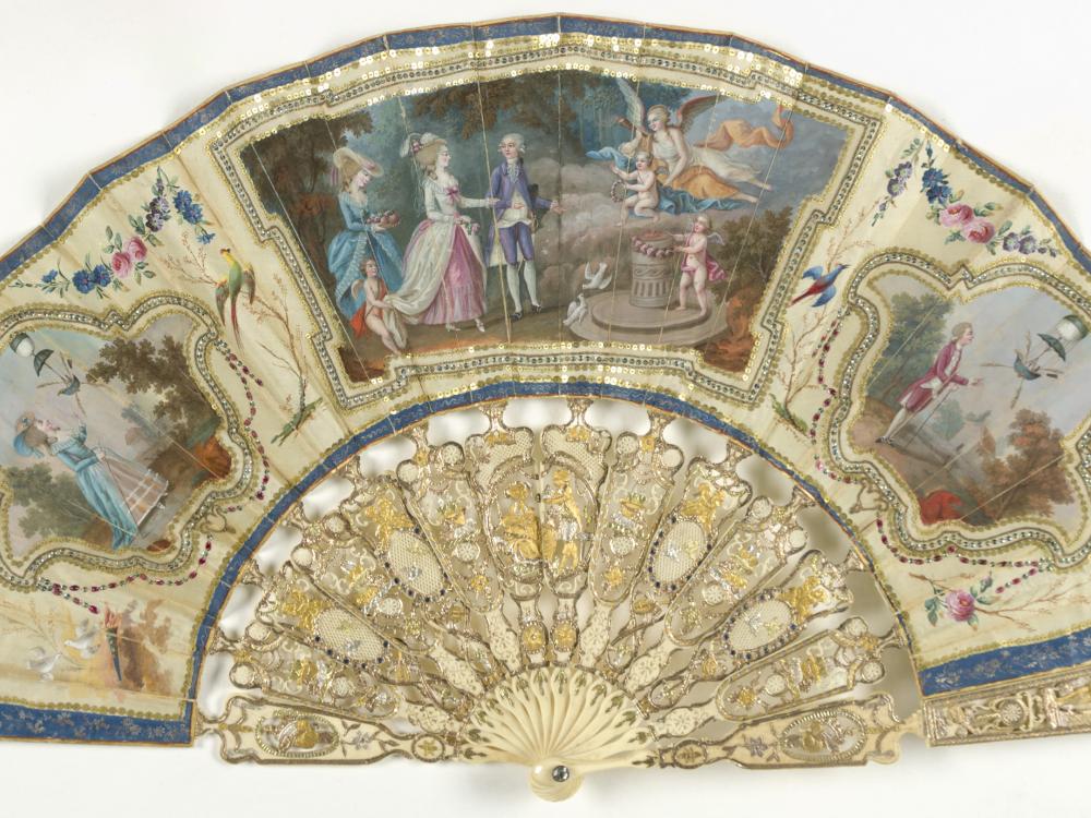 Ornate, ivory decorative fan with depictions of people watching air balloon launches.