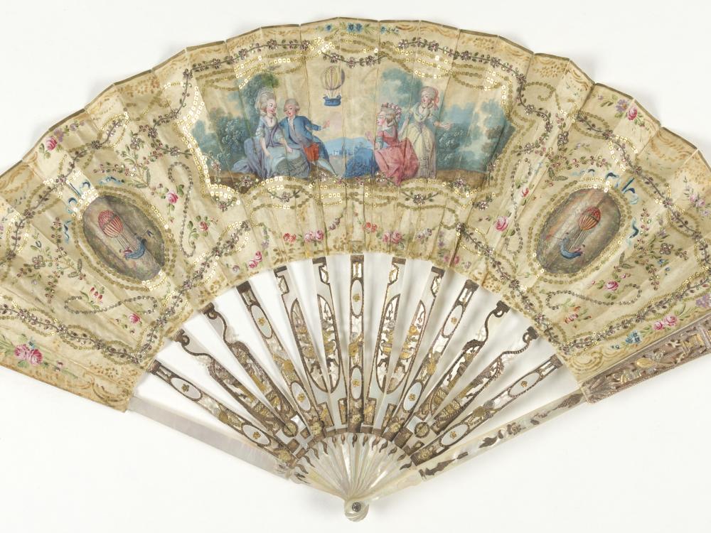 Ornate, pearl decorative fan from the eighteenth century with depictions of the first hydrogen balloon launch.