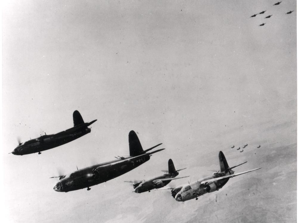 A group of four bomber aircraft fly in the sky during a mission during World War II.