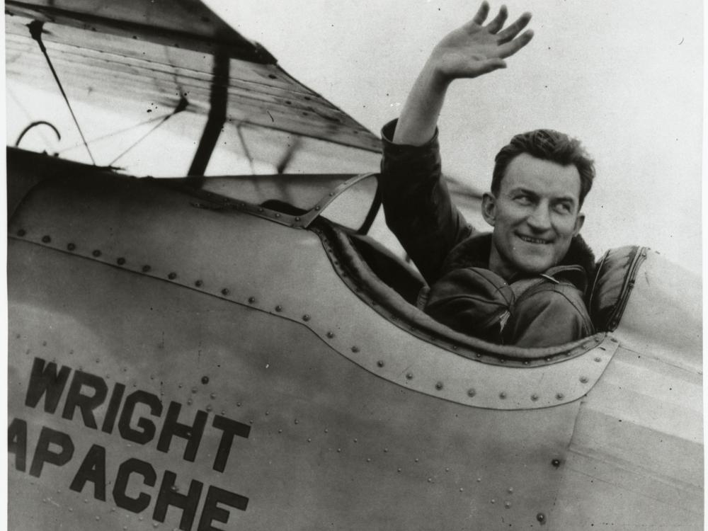 Lt. Apollo Soucek, a white male pilot, waves from the cockpit of an aircraft.