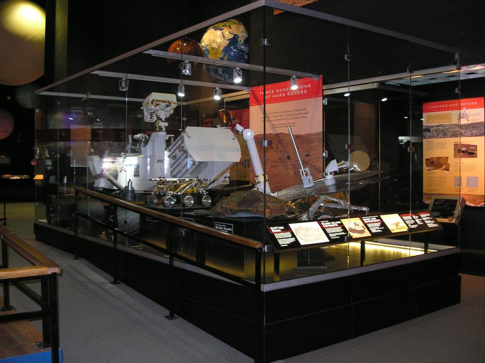 A display of three full-scale models of Mars Rovers, traveling robots used to explore Mars, on display in the Museum's Washington, D.C., building. The models are encased in glass.