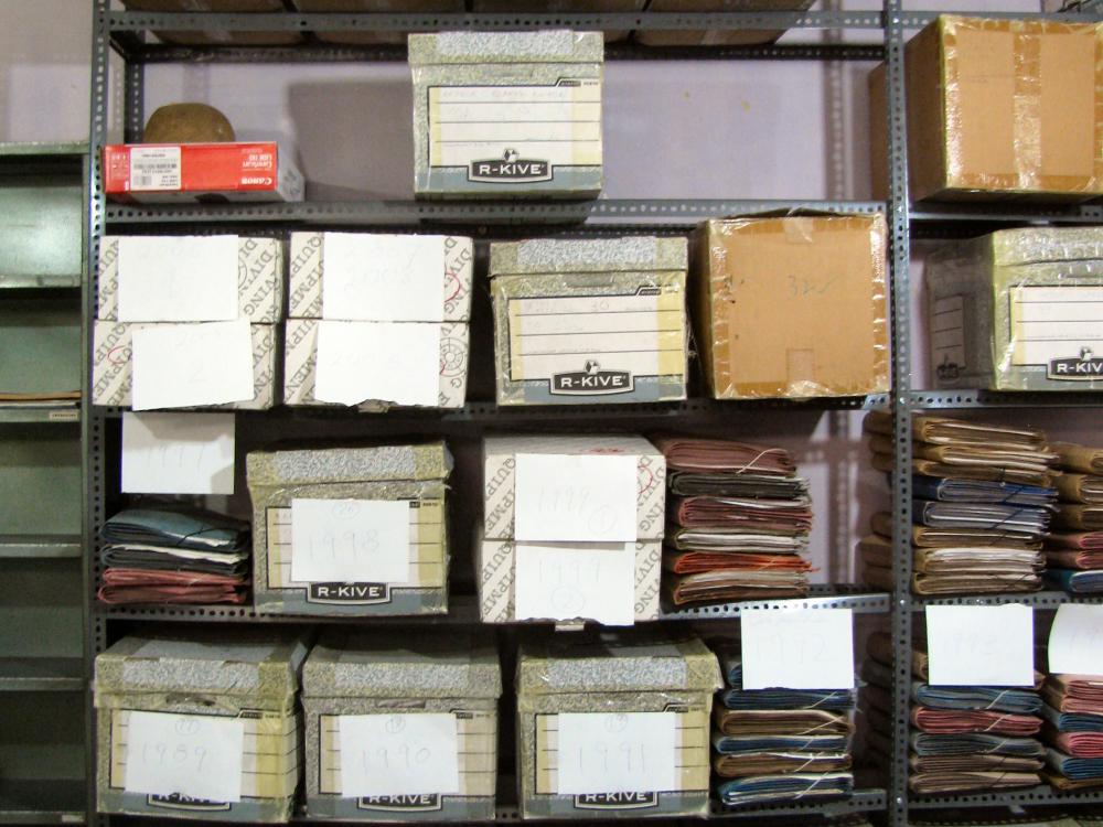 A multi-shelf storage display with twenty-one visible boxes and multiple other folders.