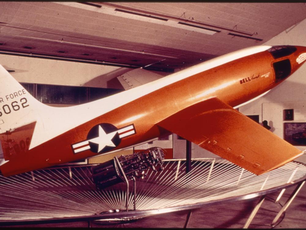 Side view of orange and white military monoplane. Registration number "6062" painted on the fin in black paint.