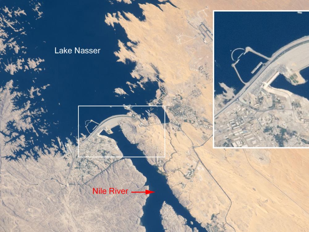 Satellite view of a lake, dam, and surrounding deserts in Egypt. A panel gives a closer perspective of the structure of the dam.