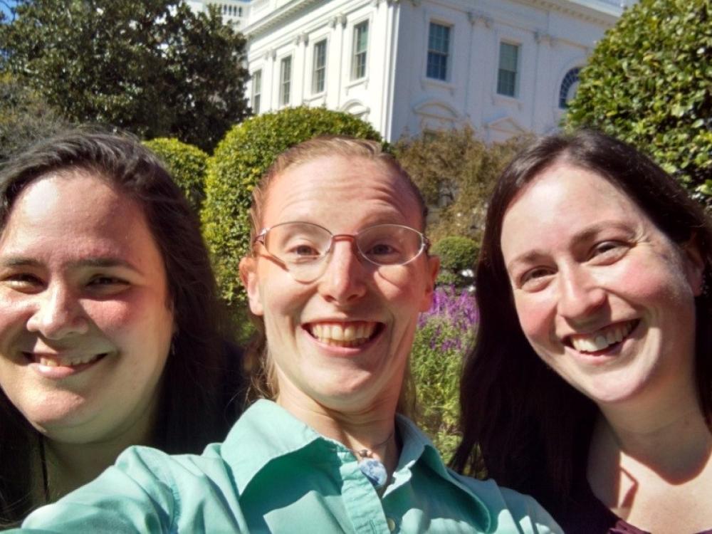 Three Museum educating staff members pose informally outside the White House.