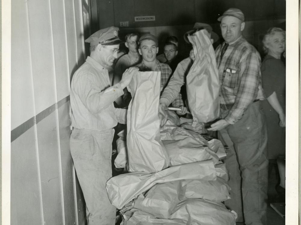 Employees of the Northwestern Aeronautical Corporation line up behind a stand of turkeys that are being given away.