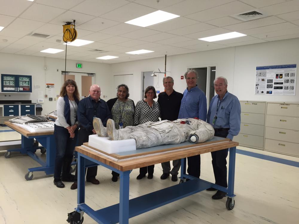 Alan Eustace, a record-holding altitude jumper, poses with members of the Museum's conservation staff on the side of Neil Armstrong's Apollo 11 spacesuit in the Museum's conservation laboratory.